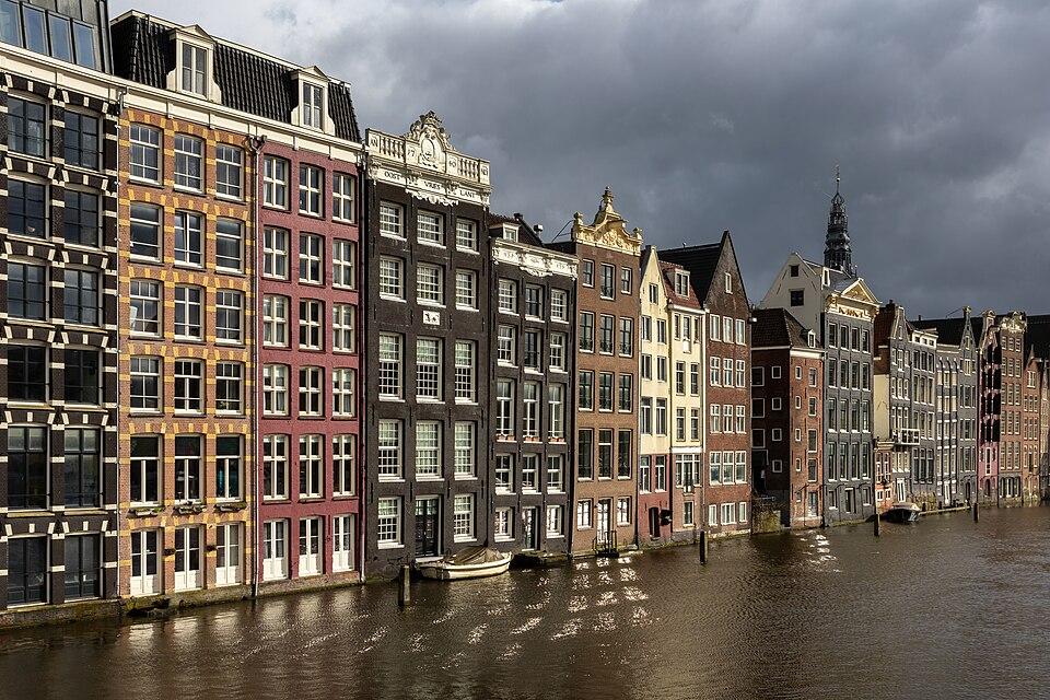 Olanda — imagine ilustrativă: Colorful canal houses at golden hour in Damrak avenue Amsterdam the Netherlands.jpg